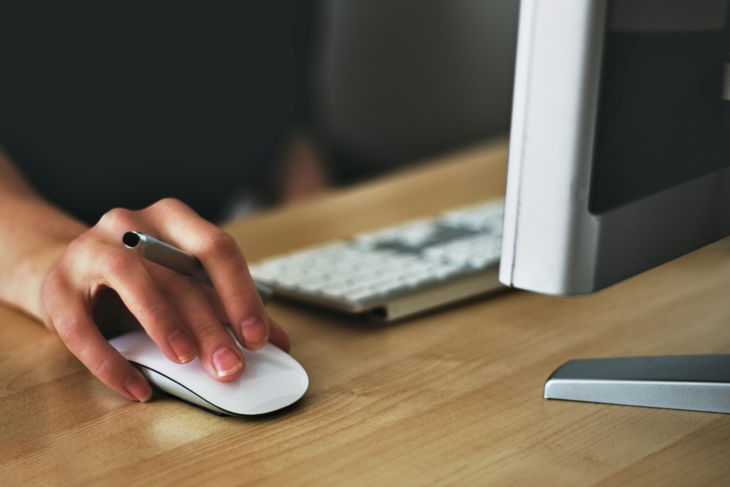 Hand auf Computermouse und aufgeklapptes Notebook